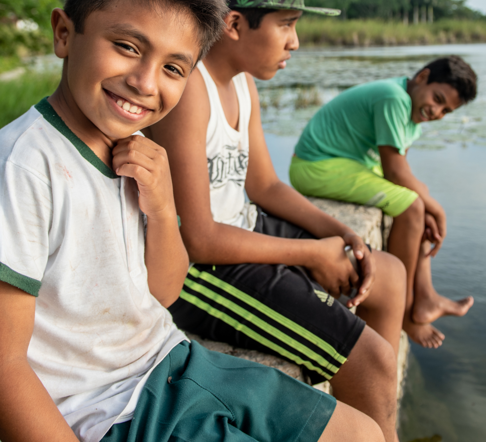 Children sitting on a riverbank smiling