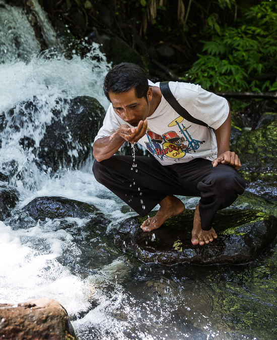 Man drinking water at waterfall