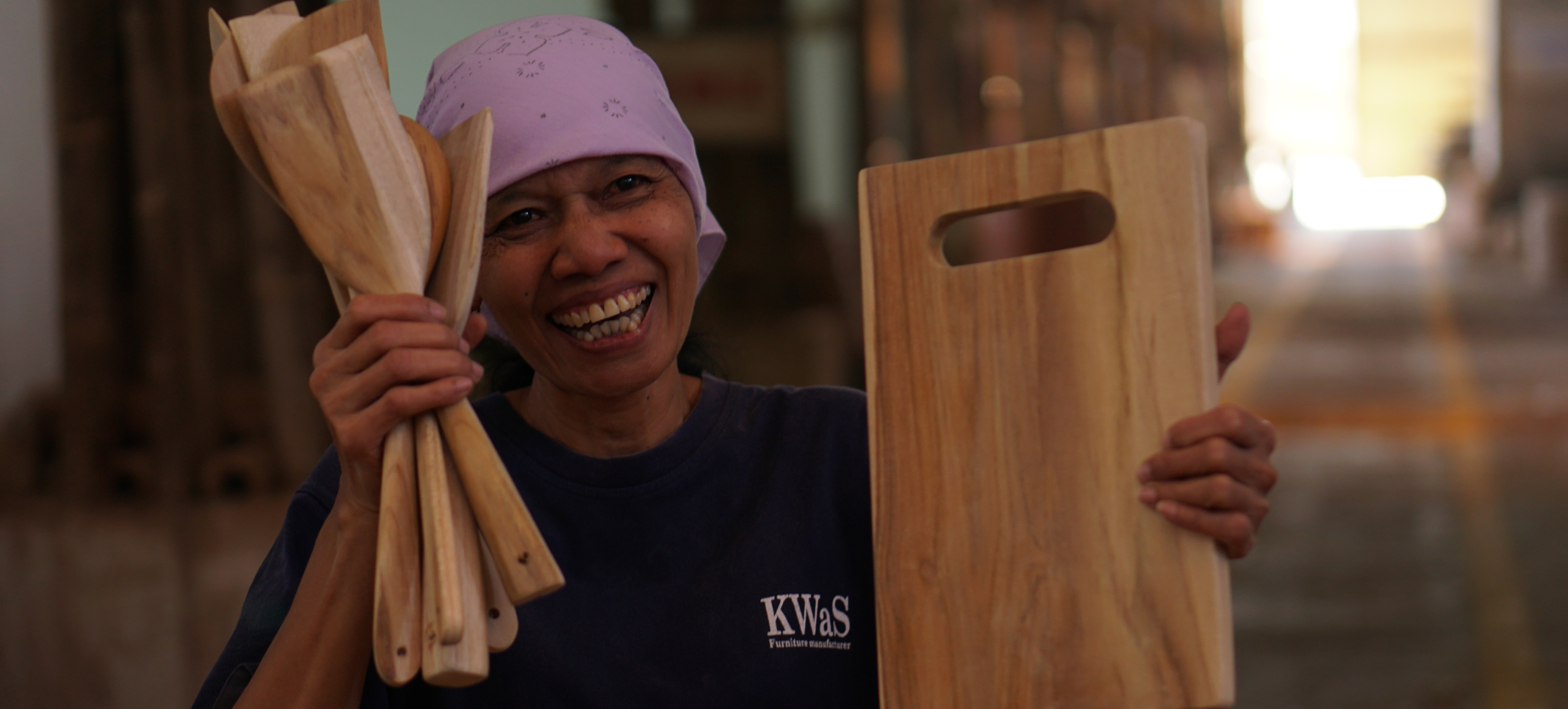 smiling woman holds up FSC certified wooden spoons and cutting board