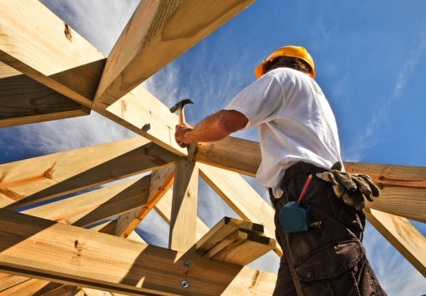 Low-angle shot of a worker hammering a house frame