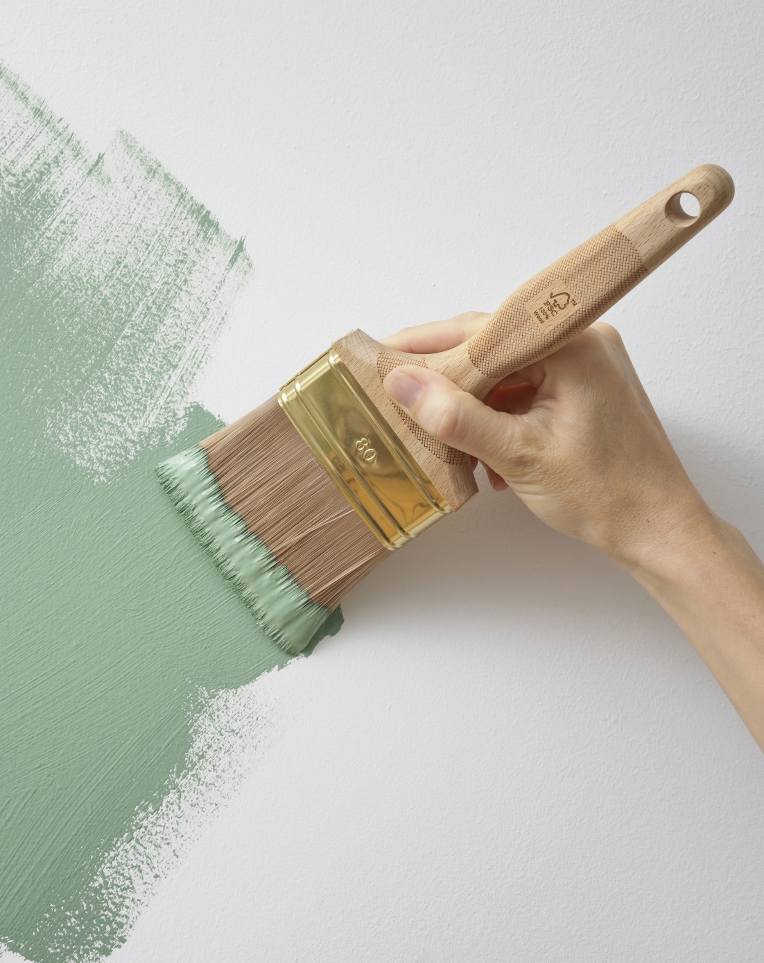 Person painting the wall with green paint with FSC certified paint brush