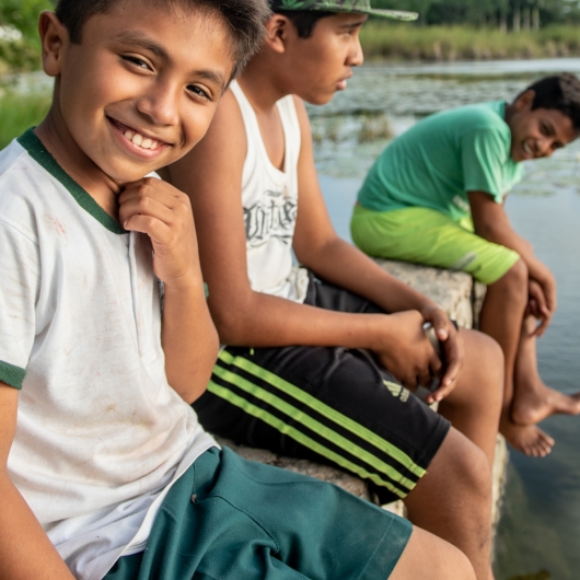 Children sitting on a riverbank smiling