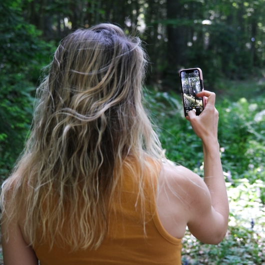 a woman with a phone in the forest 