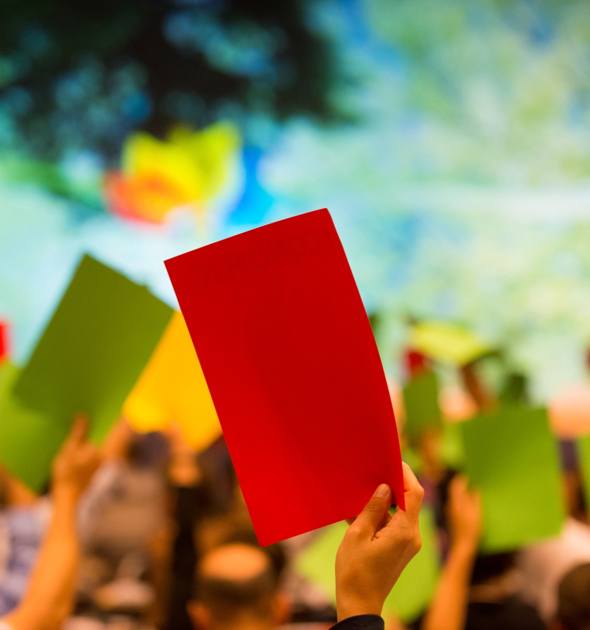 Crowd holding up red, yellow or green pages