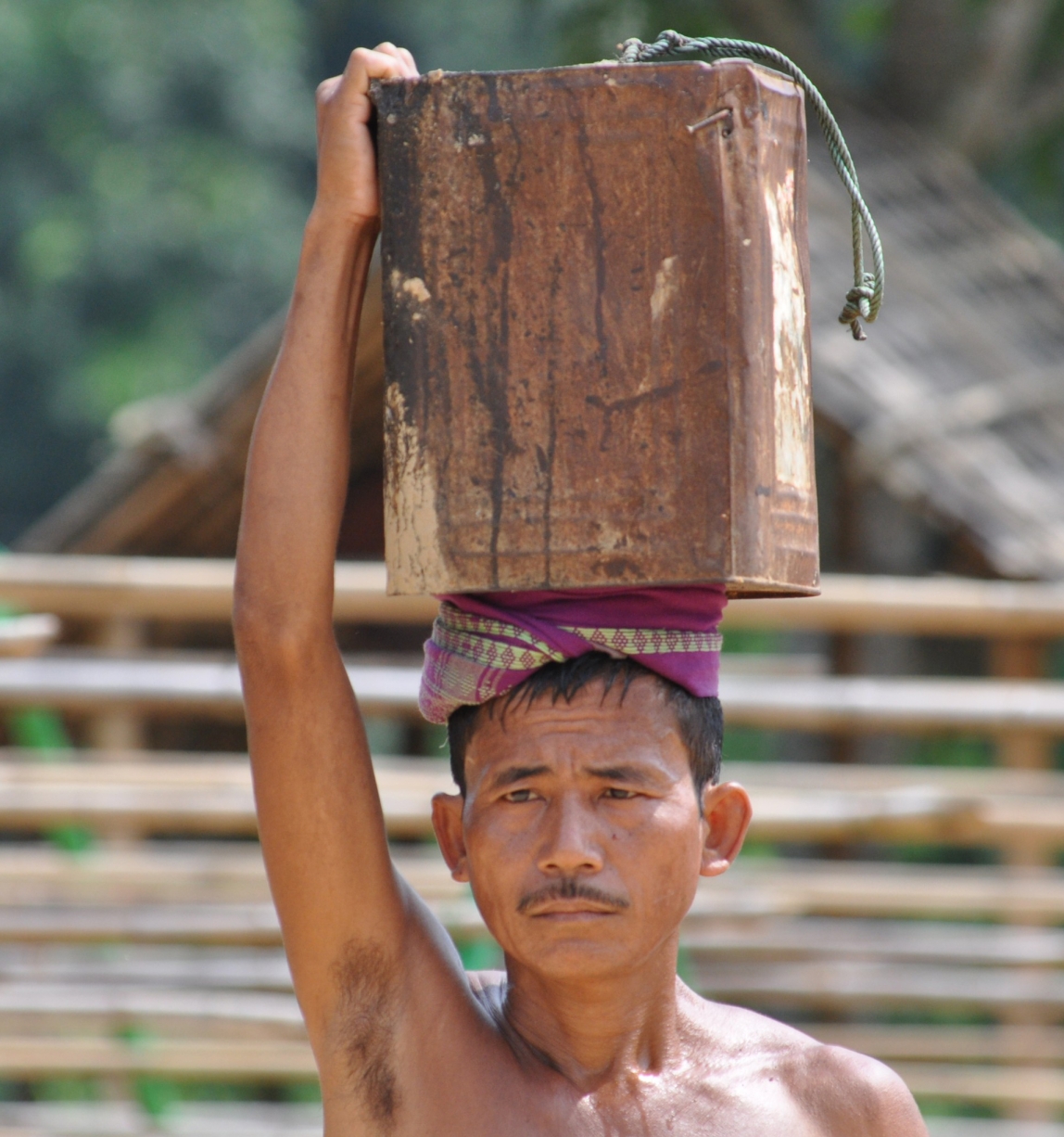 man carries piece of log on his head