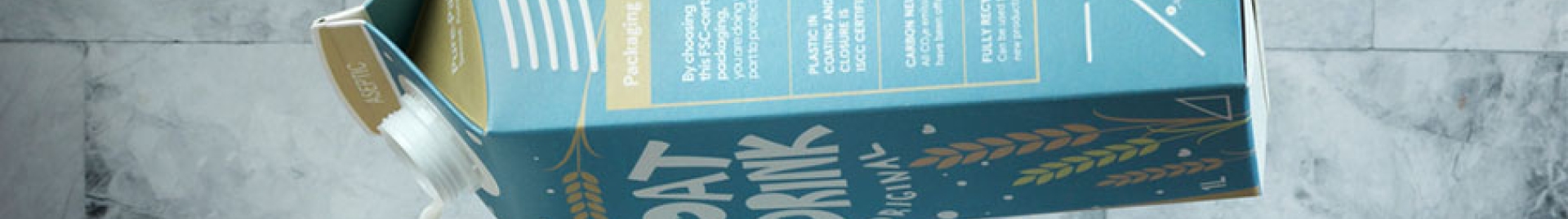 An image of a person pouring oat milk from a carton into a glass.