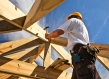 Low-angle shot of a worker hammering a house frame