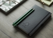 Two Green FSC Certified Pencils Atop Black Notebook with FSC logo 