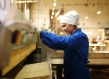 Woman worker operating saw in wood workshop