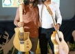 two men each holding a guitar smiling together for a picture