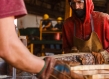 Photo of two men cutting wood planks with a bandsaw.