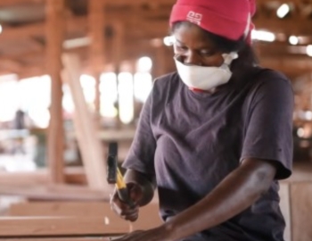 Woman hammering a nail into a wood plank