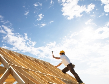 Worker hammering a wooden building frame
