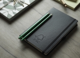 Two Green FSC Certified Pencils Atop Black Notebook with FSC logo 