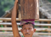 man carries piece of log on his head
